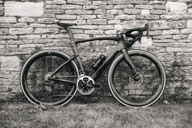 Pinarello road bike equipped with Velocite carbon wheels and disc brakes, photographed against a rustic stone wall in the UK.