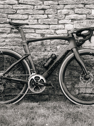 Pinarello road bike equipped with Velocite carbon wheels and disc brakes, photographed against a rustic stone wall in the UK.