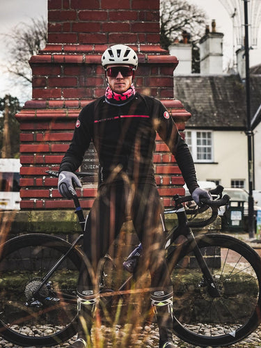 Cyclist standing with a bike in a picturesque village center with historic architecture.