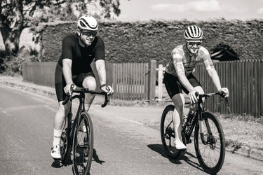 Two cyclists riding Velocite carbon road bikes on a sunny day, showcasing lightweight performance and style.