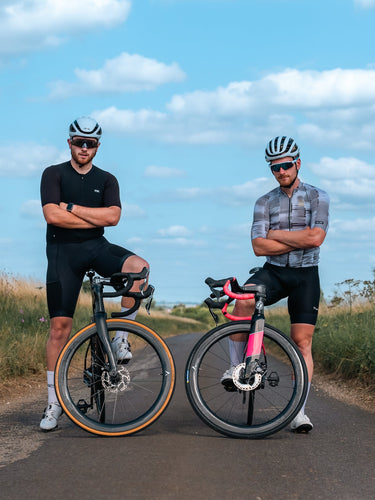 Two UK cyclists showcasing Velocite carbon road bike wheels in a scenic countryside setting for road cycling enthusiasts.